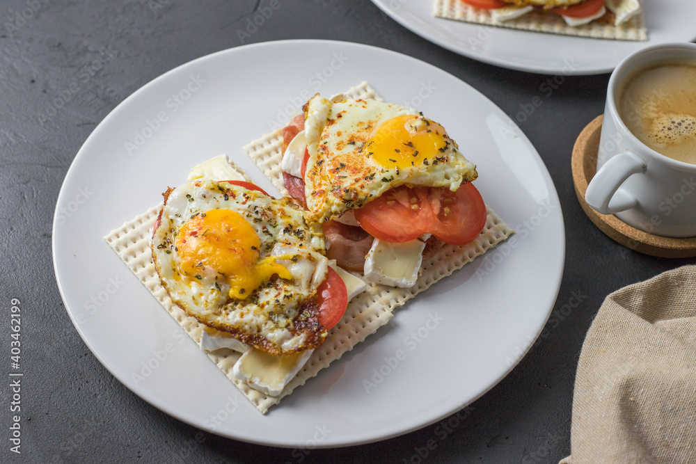Diet bread sandwiches with egg and juicy tomato on a white plate. View from above.
