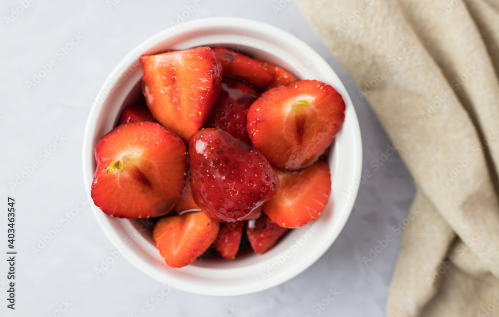 Strawberries in a bowl on a white table from above