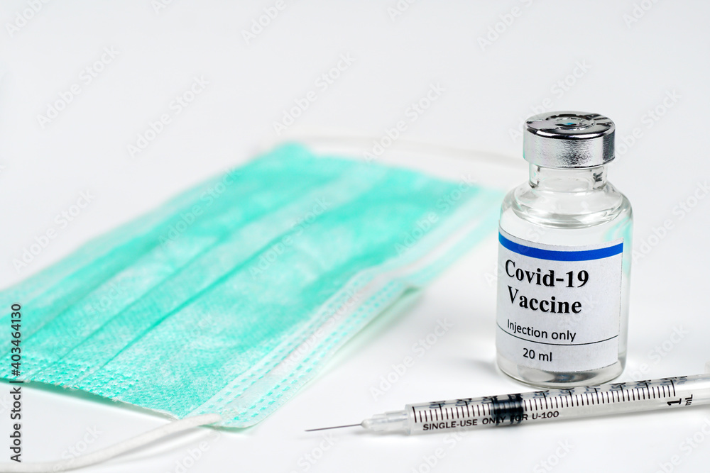 COVID-19 vaccine bottle, vials, syringes and face mask on white background with copy space. Vaccination session and immunity improvement. COVID-19 vaccine bottle, vials, syringes and face mask on white background with copy space. Vaccination session and immunity improvement.