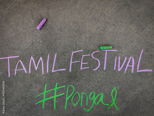 The inscription text on the grey board, Tamil Festival with (hashtag) #pongal. Using color chalk pieces.