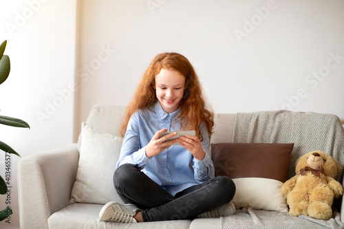 Girl using her smart phone resting on sofa