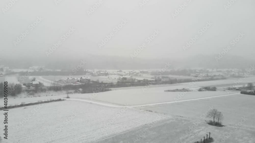 Snowy Landscape Near Countryside Village During Snowfall In Winter. - aerial descend Snowy Landscape Near Countryside Village During Snowfall In Winter. - aerial descend