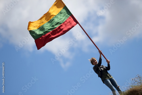Young happy woman with Lithuanian flag, sky background photo