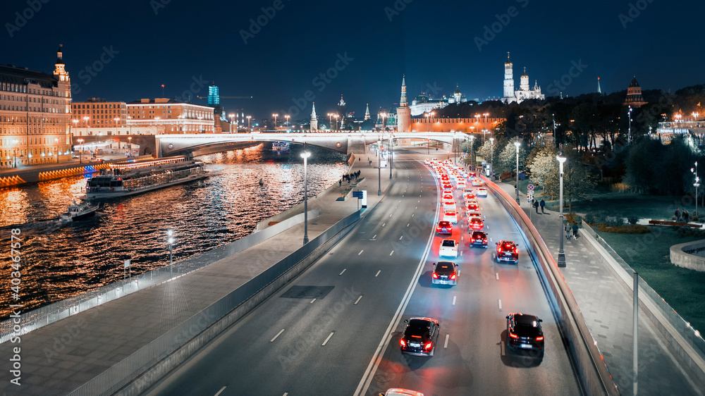 Fototapeta premium MOSCOW – OCTOBER 4, 2020: View of the Moskva River from the Bolshoi Moskvoretsky Bridge on a late autumn evening, full moon in the sky behind the clouds.