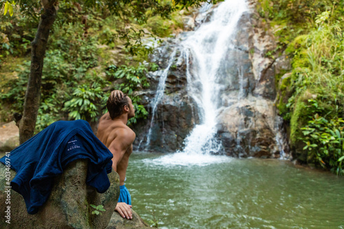 Man without shirt in waterfall 