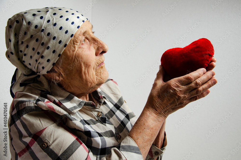 Heart in old hands close up. Grandmother with a heart in her hands as a symbol of love and kindness. March 8. An aged mother with a heart in her palms. Mothers Day. Happy International Women's Day Mom Heart in old hands close up. Grandmother with a heart in her hands as a symbol of love and kindness. March 8. An aged mother with a heart in her palms. Mothers Day. Happy International Women's Day Mom