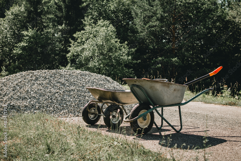 Two wheelbarrows standing near pile of gravel