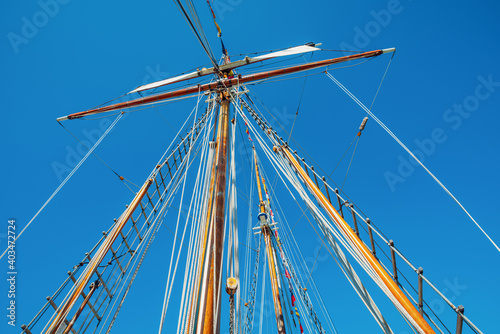 Old sailing ship wood mast, rigging of a sailing ship detail against blue sky