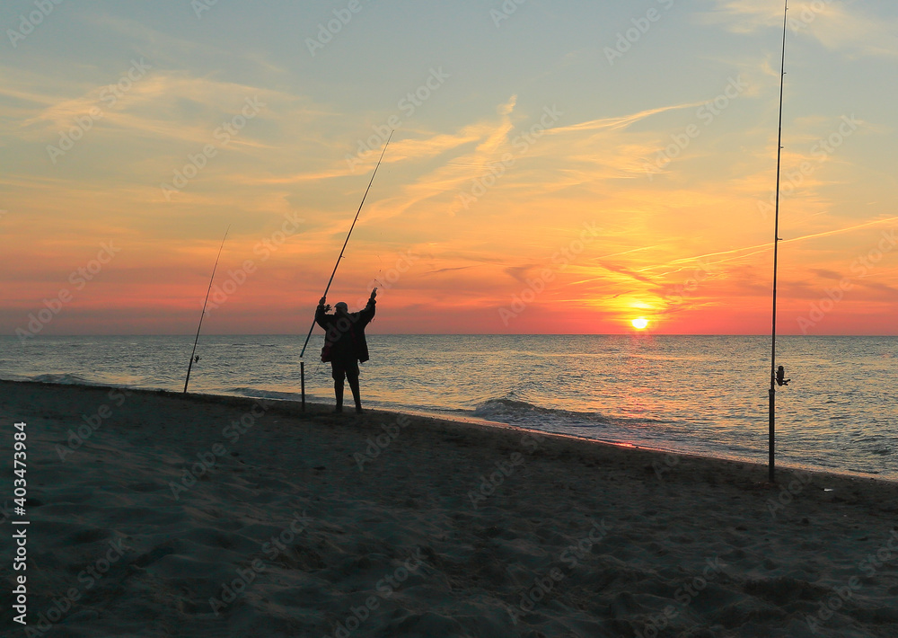 At sunset, a fisherman prepares a fishing rod.