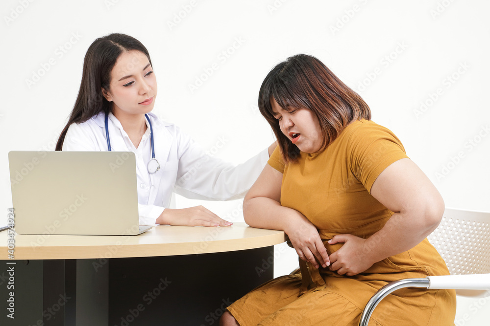 Beautiful young female doctor examines the symptoms of a fat woman sitting severe abdominal pain Food poisoning. Treatment of obesity and diabetes. The concept of healthy weight loss Beautiful young female doctor examines the symptoms of a fat woman sitting severe abdominal pain Food poisoning. Treatment of obesity and diabetes. The concept of healthy weight loss