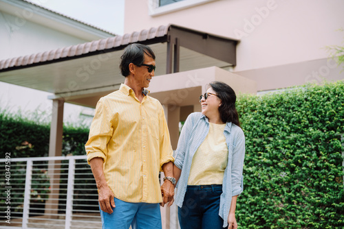 Happy asian couple wearing sunglasses standing infront of the house.