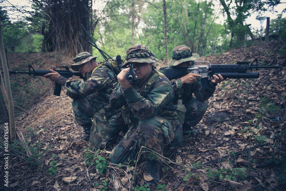Team of army soldier with machine gun moving in the forest,Thai militia soldier in combat uniforms in the wood,Wander the patrol sloping in the rainforest. Team of army soldier with machine gun moving in the forest,Thai militia soldier in combat uniforms in the wood,Wander the patrol sloping in the rainforest.