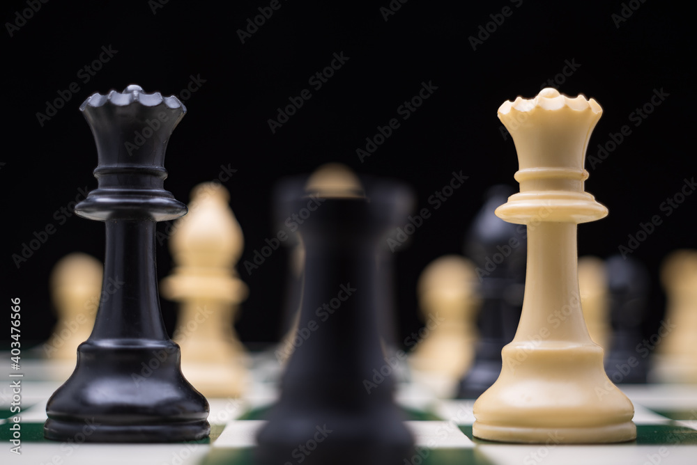 Extreme close up of chess pieces arranged on a portable chessboard before a black background. Extreme close up of chess pieces arranged on a portable chessboard before a black background.