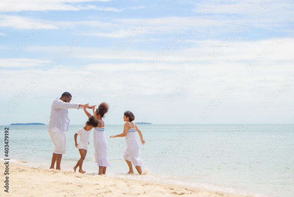 Happy African American family, father, mother and daughters happiness vacation relax with sea background.Parents with children enjoying vacation on beach.