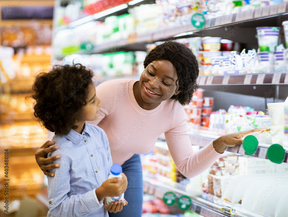 Young black mother with her daughter shopping for dairy products at supermarket Young black mother with her daughter shopping for dairy products at supermarket