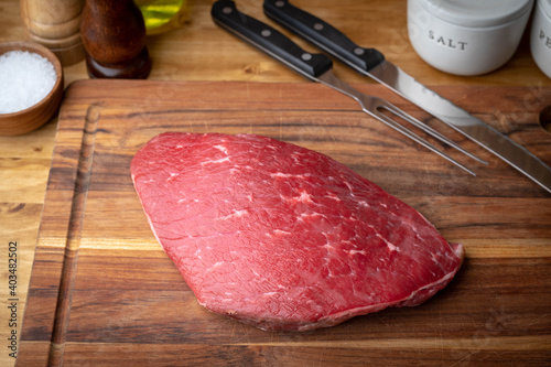 raw flank steak on wooden cutting board