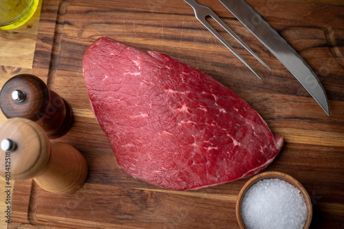 raw flank steak on wooden cutting board
