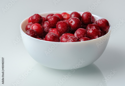red frozen cherry in a white salad bowl on a white background