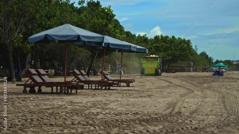 Tractor technic for cleaning the sea beach from garbage stands on the sand after throwing plastic garbage from the sea on the island of Bali in the city of Kuta