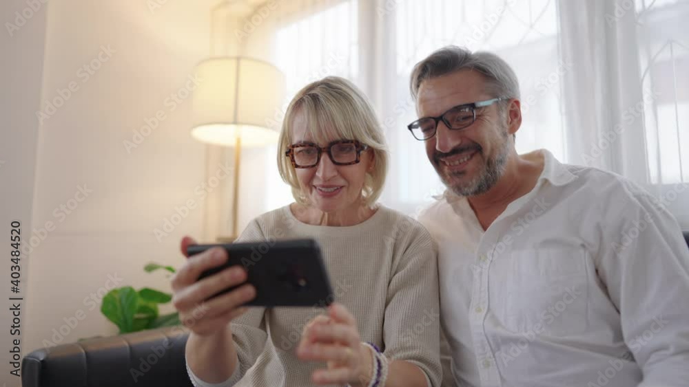 Happy couple elderly retirement using mobile phone to video conference call with family in the living room atmosphere, Social distancing family during coronavirus pandemic. Happy couple elderly retirement using mobile phone to video conference call with family in the living room atmosphere, Social distancing family during coronavirus pandemic.