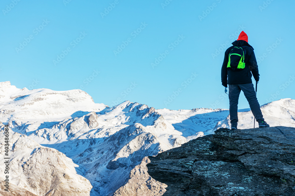 A mountaineer contemplating the landscape of the Sierra Nevada mountains with snow.