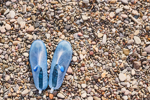 Rubber blue women's slippers for swimming on a pebble beach