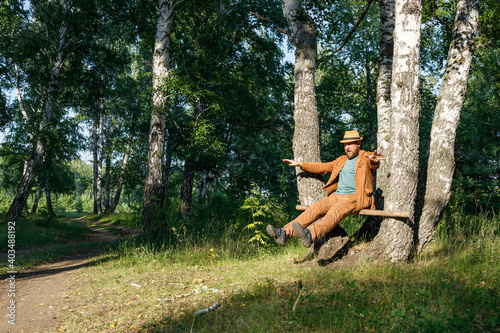 bearded man tries to maintain balance while sitting on a perch in the forest
