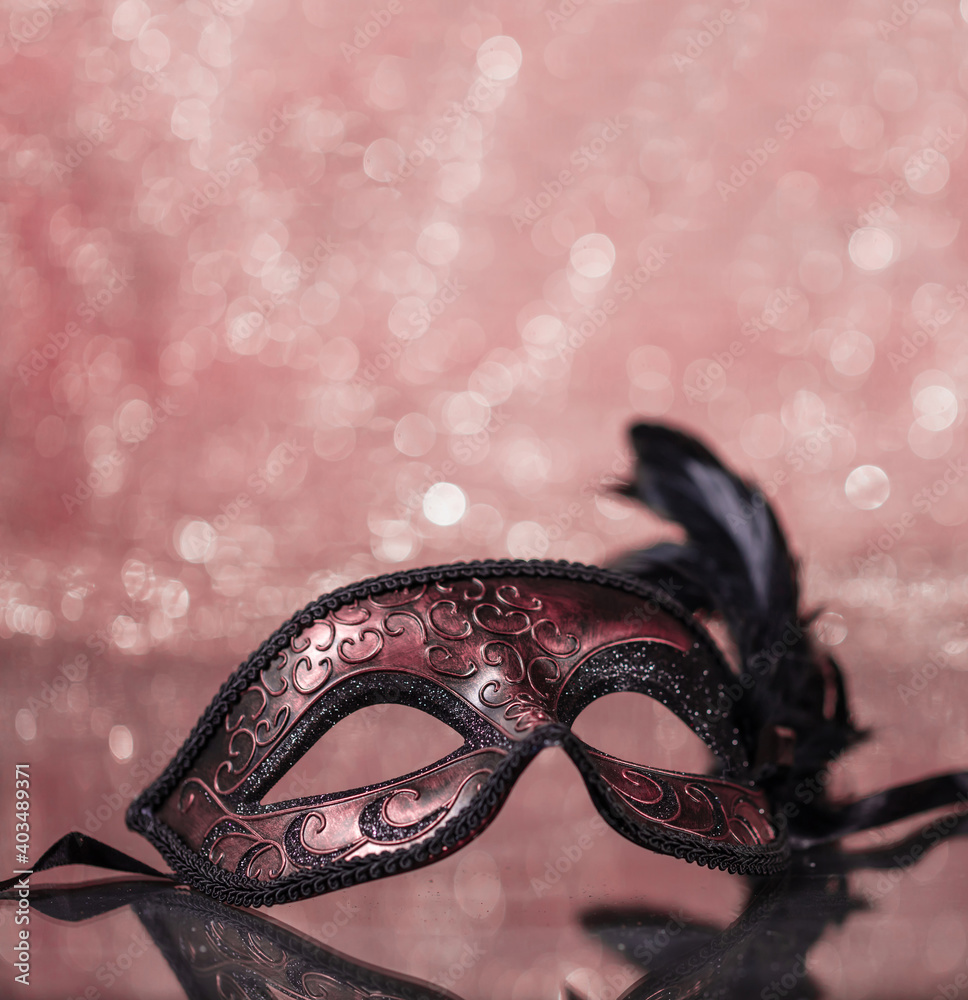 Carnival mask with feathers on pink bokeh background.