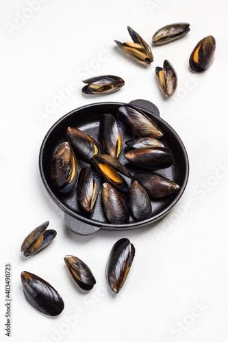 Shellfish Mussels in frying pan. Mussels are scattered on table