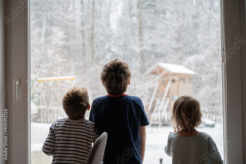 Fényképezés Kids looking out the window while snowing