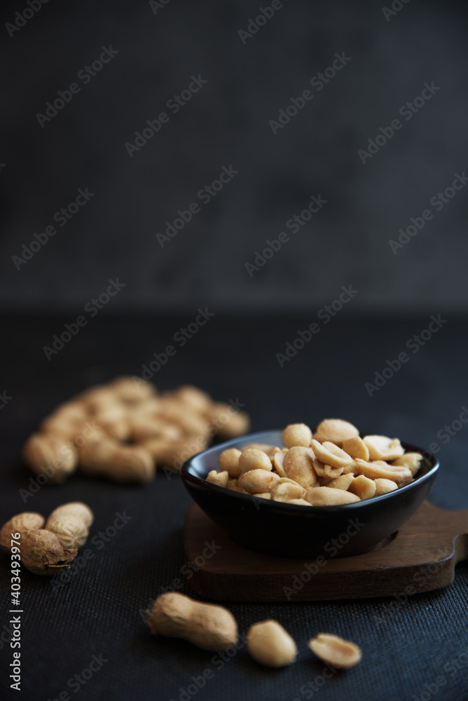 Peeled peanuts in a small bowl, in the back whole peanuts.
