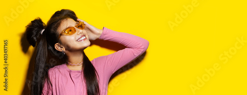 Studio portrait of smiling teenage girl on background of yellow color with copy space. Panoramic photo. © Lalandrew