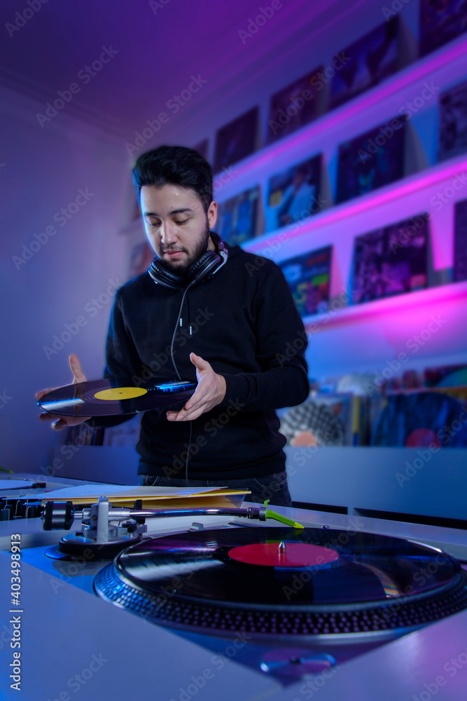 Joven dj colocando un disco de vinilo en un tornamesa, para mezclar música  en una tienda de discos de vinilo. Stock Photo