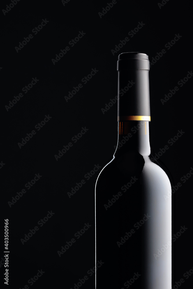 An unopened bottle of red wine on a black background. An unopened bottle of red wine on a black background.