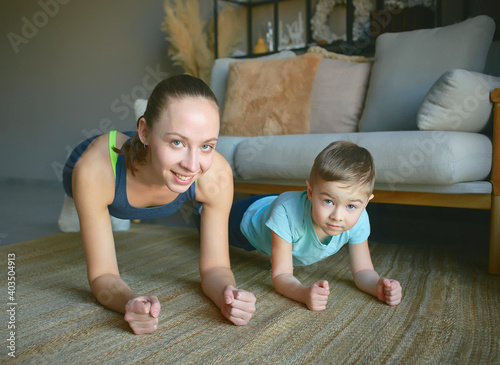 mom and son play sports at home. they perform the plank exercise. a smile on their faces.