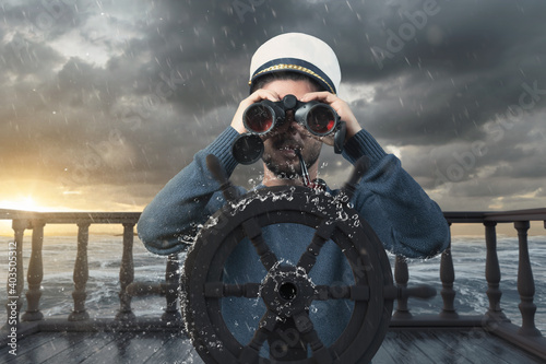 helmsman with binoculars and cap on stormy seas viewing the coast