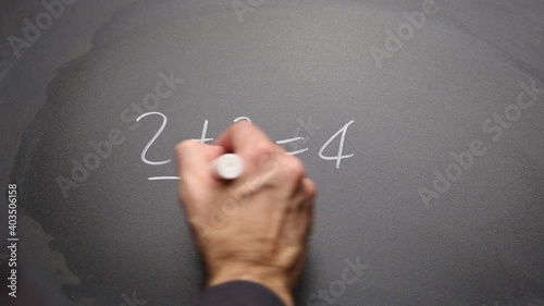 Hand writing “2+2=4” on chalkboard and highlighting. Concept of math and basic simple solution