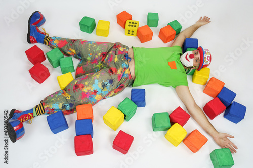 The clown lies on the floor among the colored cubes. Isolated on white