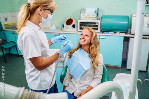 Beautiful young girl at the dentist appointment. An experienced dentist checking the health of patients teeth in a modern dental office. Portrait of smiling girl on a dental chair in dentistry