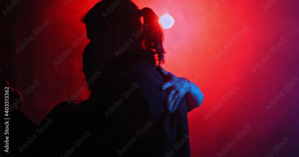 Silhouette of a dancing couple in a dark room with smoke, bright red and blue lamps. Man looks passionately at the woman and circles with her in a dance, tango. 4k, ProRes Silhouette of a dancing couple in a dark room with smoke, bright red and blue lamps. Man looks passionately at the woman and circles with her in a dance, tango. 4k, ProRes
