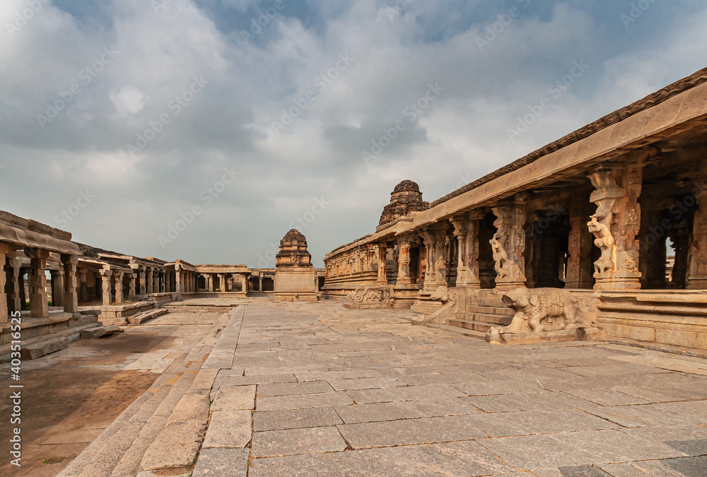 Hampi, Karnataka, India - November 5, 2013: Sri Krishna temple in ruins. View along the main building, the Mandapa,m and inner sanctum, all in shades of brown stone under blue cloudscape.