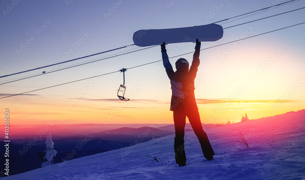 Fototapeta premium Silhouette of snowboarder against setting sun in lift ski resort