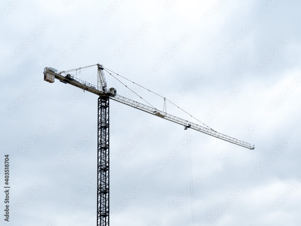 silhouette of a construction crane against a cloudy sky on a high rise building site