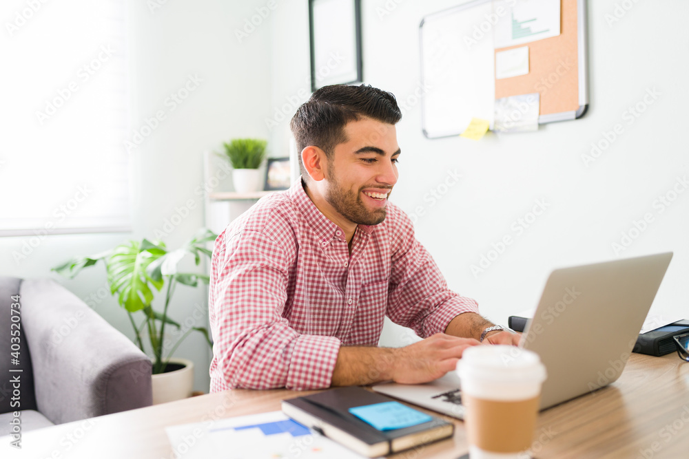 Smiling guy at the office is typing on his laptop Smiling guy at the office is typing on his laptop