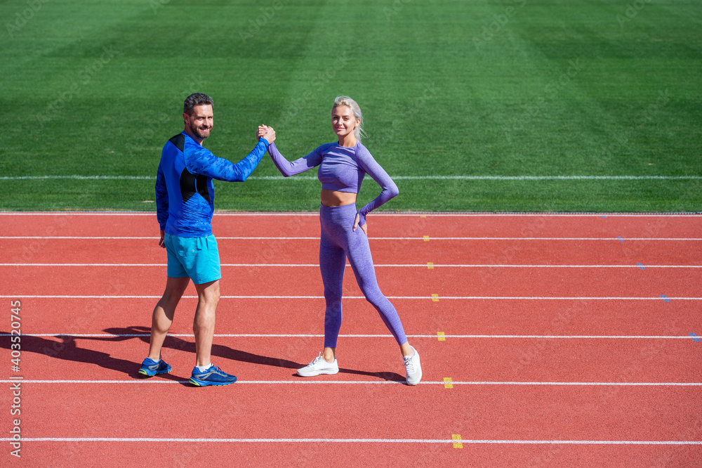sport couple fitness partners celebrate team win with gesture of shake hand after exercising or compete in armwrestling on stadium running track arena outdoor, sport success