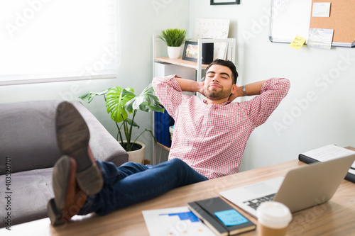 Attractive guy reclining on his office desk with a peaceful expression