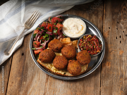 falafel with mazes and a fork on a metal plate on wooden background
