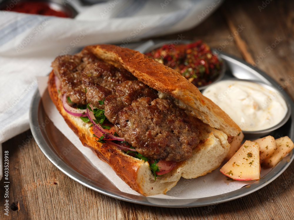 meatball sandwich with mezes on a metal plate on wooden background
meatball sandwich with mezes on a metal plate on wooden background