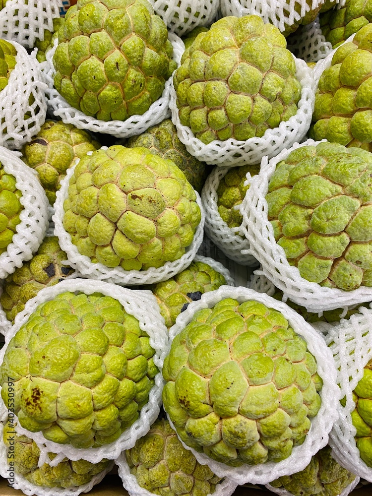 Obraz premium Close-up photo of Sugar Apple in market. Group of fruits background. Sweetsop or Custard Apple.