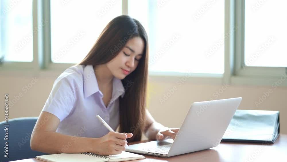 Smart student is typing on a laptop and writing in his notebook. Busy worker student working on modern tech notebook device. Smart student is typing on a laptop and writing in his notebook. Busy worker student working on modern tech notebook device.